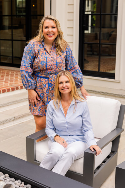 realtor team one sitting one standing on a house patio during photo session