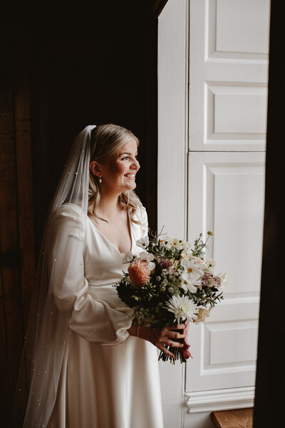 Pregnant bride smiling, holding a wild flower bridal bouquet