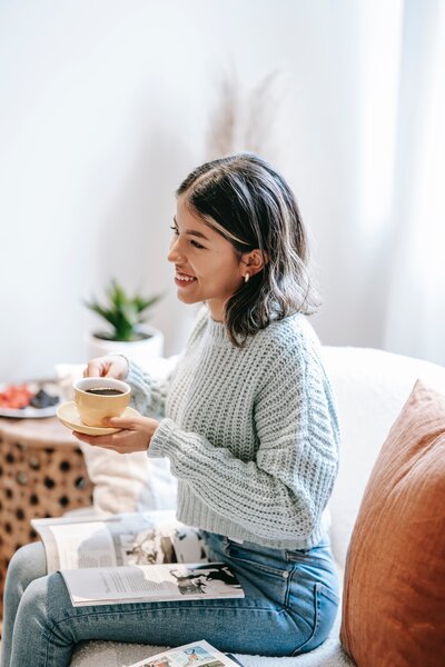 A smiling woman gracefully holds a cup, radiating joy and contentment