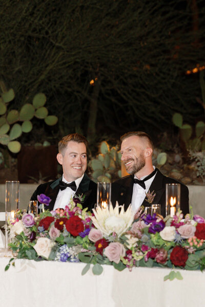 LGBTQIA+ couple cheers cocktails on their wedding day at the Desert Botanical Garden in Phoenix, Arizona.