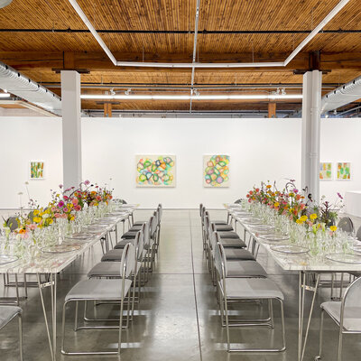 Tables topped with small glass vases of bright flowers at a modern art gallery wedding reception.