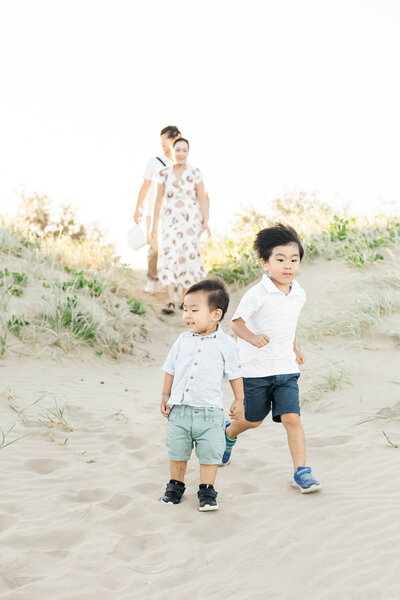 Candid family portrait of two little boys running along the sand on Kinka Beach, while being photographed by Yeppoon Family photographer Julie-Anne Photography.