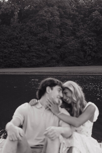 Joyful couple laughing together by a lakeside in a black-and-white photo — candid and romantic moment captured by EC Photography in Alabama