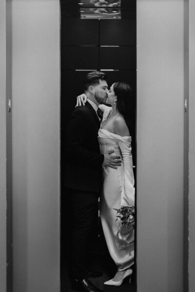 A couple kissing in an elevator with a moody black and white aesthetic, shot by Stacey Vandas Photography