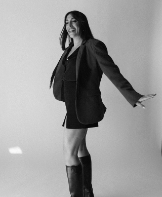 Dani Antony twirling in a photo wearing a blazer, mini skirt and boots