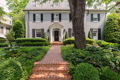 Brick pathway leading to home surrounded by lush greenery