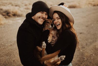 couple smiling and holding a dog