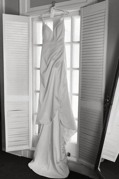 Classic designer wedding dress hanging on window inside historic Grand Island Mansion