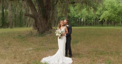 groom holding bride from behind under oak tree