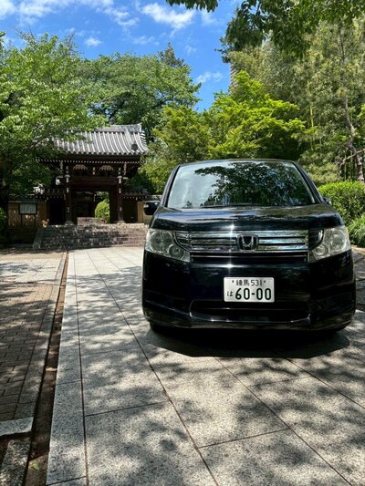 Front view of the Honda Stepwagon parked in front of a serene Japanese temple, blending modern luxury with cultural heritage.
