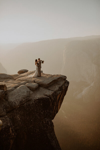 Eloping couple stands on cliff edge in Yosemite