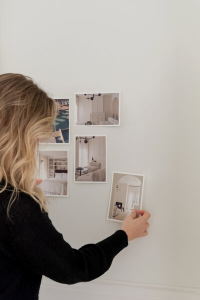 Girl Pinning photos to a wall to decide layout