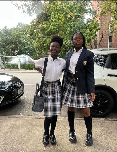 two girls in school uniform on the sidewalk