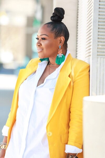 Black woman web designer wearing bright yellow jacket standing outside
