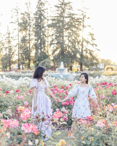 Mom and teenage daughter holding hands while walking through blooming roses at San Jose rose garden