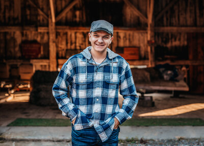 High school senior guy in plaid shirt posing in front of a fence for senior portraits in Greeley Park Nashua NH