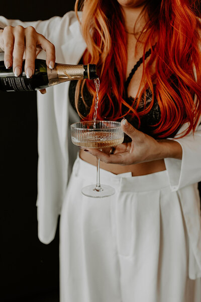 woman with red hair pouring a glass of champagne