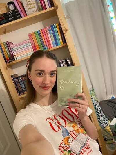 Woman posing for camera holding copy of Feels Like Coming Home by Rebecca Wrights