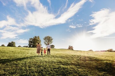 family walks uphill with vast sky and beautiful light