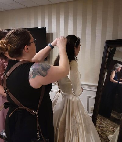 a photographer helping the bride get her veil on