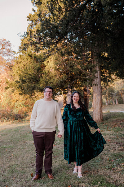 A couple holds hands and faces the camera smiling.
