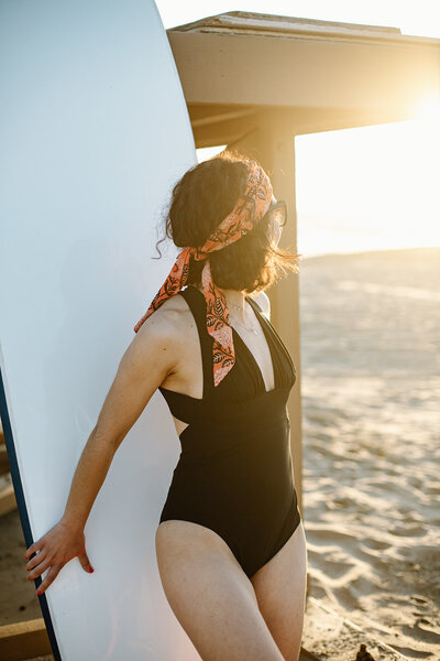 a woman in swimwear with a surfboard at the beach for her California brand photoshoot