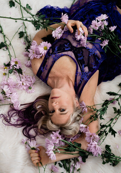 Portrait of a blonde woman laying with flowers