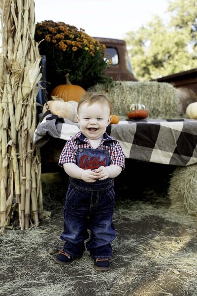 One-year-old baby boy celebrating his first birthday, smiling joyfully in front of a fun, colorful backdrop