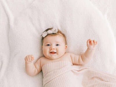 newborn baby laying in white blankets best newborn photographers fort worth