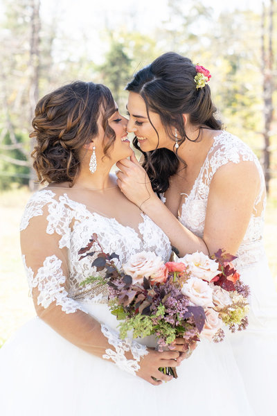 Same sex female couple holds bouquet and kisses