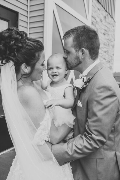 Black and white photo of bride groom and daughter giggling  by Iowa City wedding photographer Sabrina Wilham