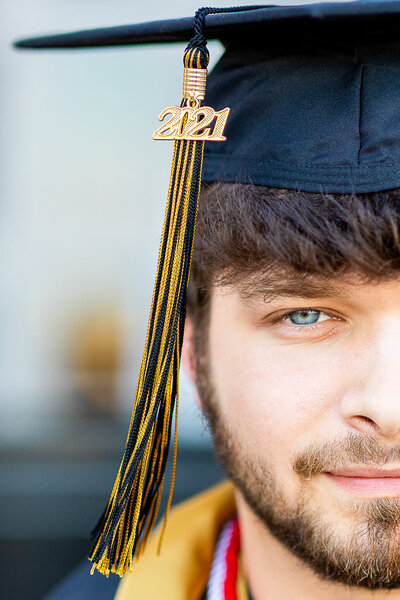 A senior male in a black cap and gown at his high school