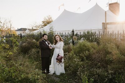Bride and groom standing in a garden outside a marque at new Jersey wedding