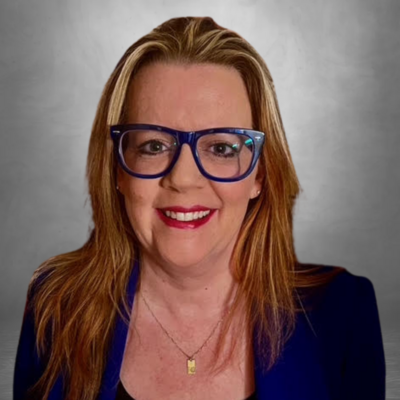 woman with blonde hair wearing a blue jacket and blue eyeglasses