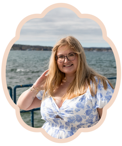 Woman with blonde hair standing by lake with wind in hair