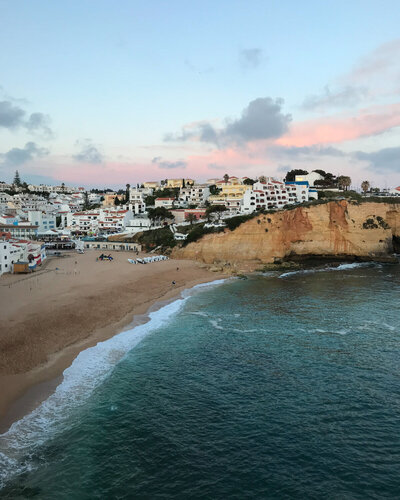 sunset with buildings on cliff and ocean