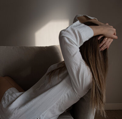 A woman in a yellow orange shirt looking upset.  Representing the importance of anxiety treatment for women in Brooklyn & Manhattan. With support from an anxiety therapist you do not have to feel like this.