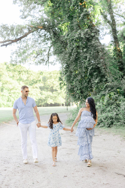 Newport Photographer Serving CT, RI, and beyond | The Corteses | Family of three wearing hints of blue walking hand in hand