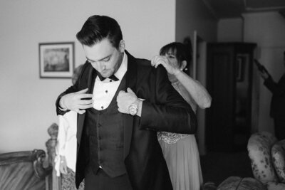 Le marié se prépare avec sa mère pour son mariage en mettant son veston.