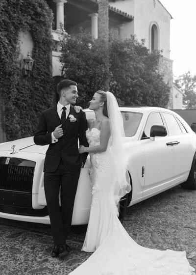 Bride and groom pose together in front of a Rolls Royce at Blackstone Country Club.