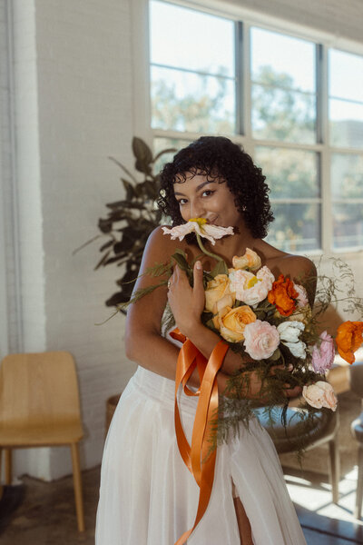 A bride with her arms wrapped around her holding a bouquet of flowers.