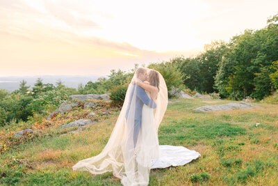 Bride and Groom kissing outside at sunset covered in a wedding veil