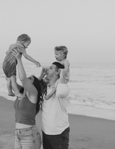 Stevie Davis' family enjoying a sunny day at the beach with their son and daughter, playing in the sand and splashing in the waves.