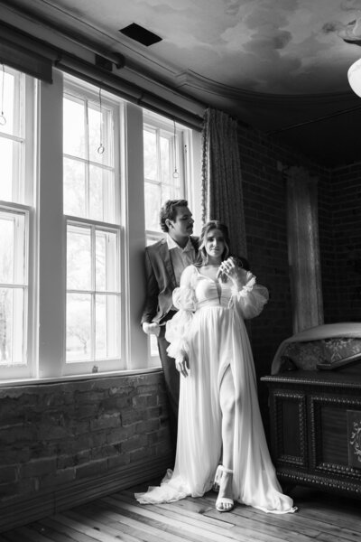 Bride and groom sharing a quiet moment indoors by a large window, with soft natural light illuminating their Kentucky wedding day.