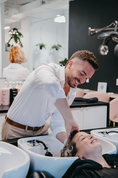 Stylist at Salon Beau providing a relaxing hair wash service, preparing for a balayage or lived-in color treatment.