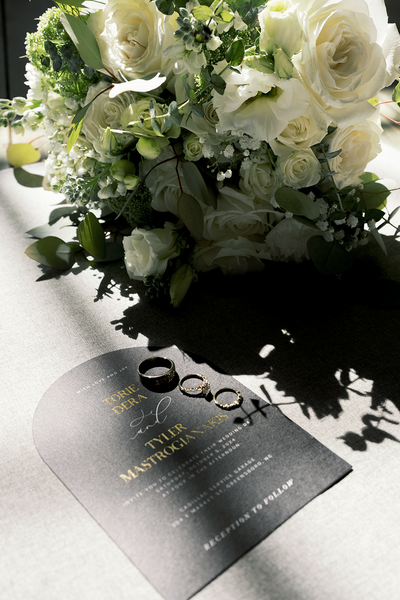 Flay lay of the wedding invitation, bouquet, and wedding wings from a luxury wedding | Megan Smith Photography 