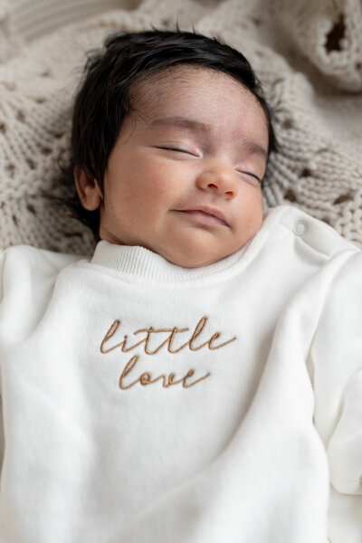Lifestyle newborn photography session with two moms holding baby in cozy nursery with natural light— captured by Alliston and Barrie maternity, newborn, and family photographer.