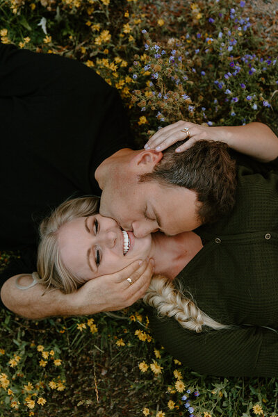 Photo of two women embracing outside while their dog runs by with mountains in the background taken by Adventure elopement photographer in telluride