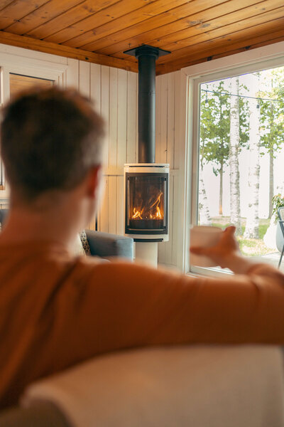 Man drinking from glass in front of fireplace