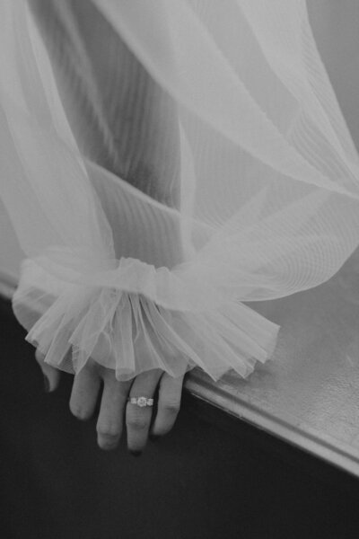 close up of a bride's arm showing through a sheer and puffy sleeve on a wedding dress